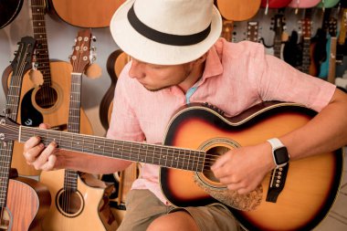 Genç bir müzisyen gitarı gitar dükkanında test ediyor..