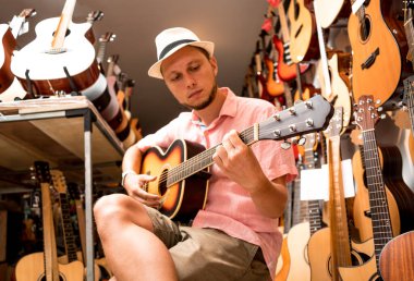 Genç bir müzisyen gitar dükkanında klasik gitar akort ediyor..