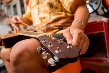 Gitar dükkanında gitarın tellerini değiştiren genç bir müzisyen..