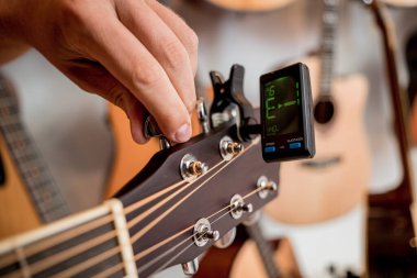 Genç bir müzisyen gitar dükkanında klasik gitar akort ediyor..