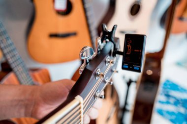 Genç bir müzisyen gitar dükkanında klasik gitar akort ediyor..