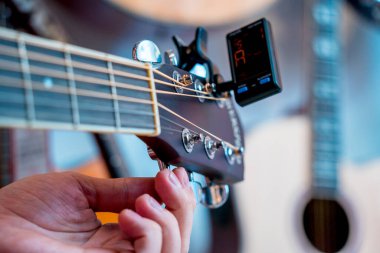 Genç bir müzisyen gitar dükkanında klasik gitar akort ediyor..