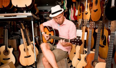 Genç bir müzisyen gitar dükkanında klasik gitar akort ediyor..