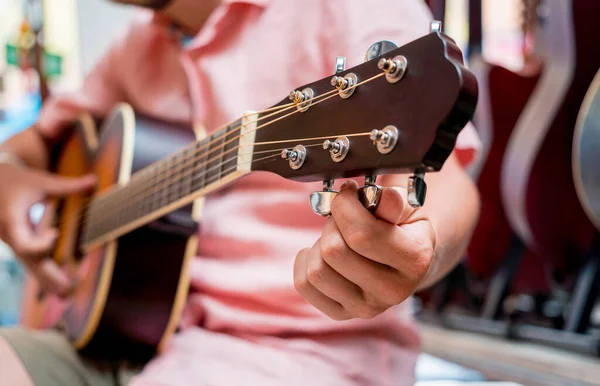 Jovem Músico Afinando Uma Guitarra Clássica Uma Loja Guitarra — Fotografia de Stock