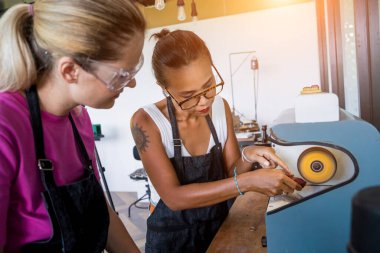 Öğretmen kuyumcu ve öğrenci atölyede mücevher parlatıyorlar..