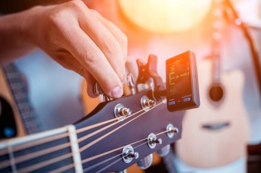 Genç bir müzisyen gitar dükkanında klasik gitar akort ediyor..