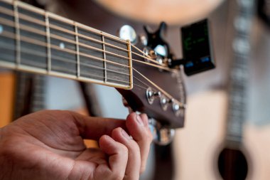 Genç bir müzisyen gitar dükkanında klasik gitar akort ediyor..