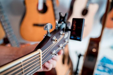 Genç bir müzisyen gitar dükkanında klasik gitar akort ediyor..