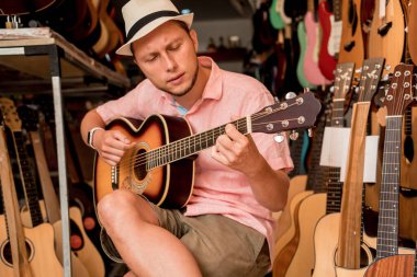 Genç bir müzisyen gitarı gitar dükkanında test ediyor..
