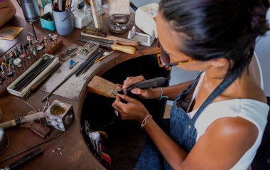 Genç bayan kuyumcu atölyede mücevher yapıyor..