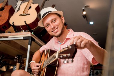 Genç bir müzisyen gitar dükkanında klasik gitar akort ediyor..