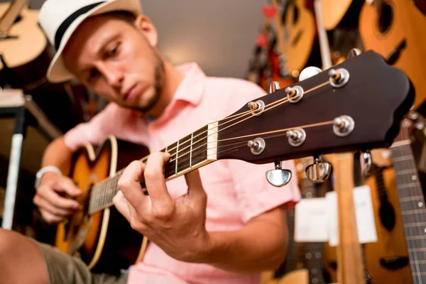 年轻音乐家在吉他手商店里调音古典吉它 — 图库照片