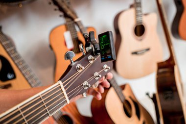 Genç bir müzisyen gitar dükkanında klasik gitar akort ediyor..