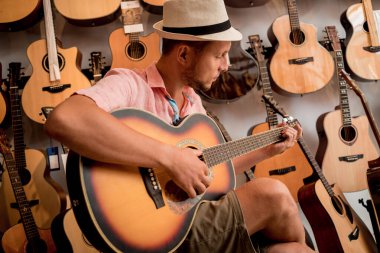 Genç bir müzisyen gitarı gitar dükkanında test ediyor..