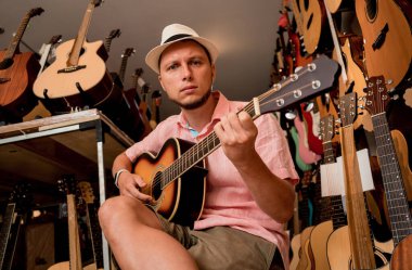 Genç bir müzisyen gitarı gitar dükkanında test ediyor..