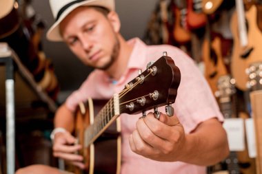 Genç bir müzisyen gitar dükkanında klasik gitar akort ediyor..