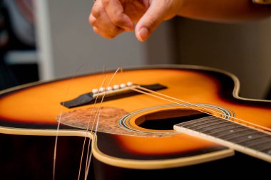 Gitar dükkanında gitarın tellerini değiştiren genç bir müzisyen..