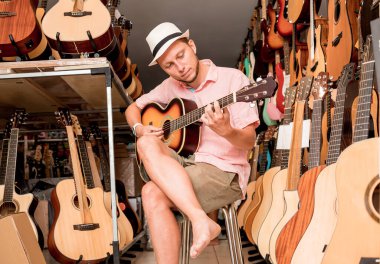 Genç bir müzisyen gitarı gitar dükkanında test ediyor..