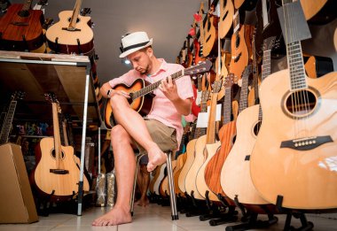 Genç bir müzisyen gitarı gitar dükkanında test ediyor..