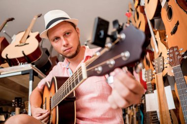 Genç bir müzisyen gitar dükkanında klasik gitar akort ediyor..