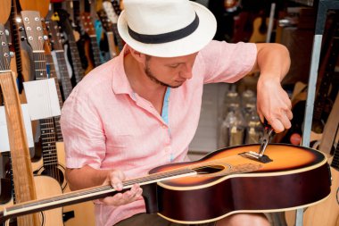 Gitar dükkanında gitarın tellerini değiştiren genç bir müzisyen..