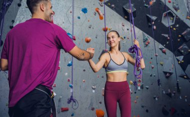 Renkli tutacakları ve ipleri olan yapay bir duvara karşı güçlü bir çift tırmanıcı.
