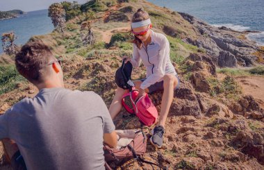 Mutlu genç çift okyanus kıyısındaki dağların tepesine tırmandıktan sonra rahatlıyor..