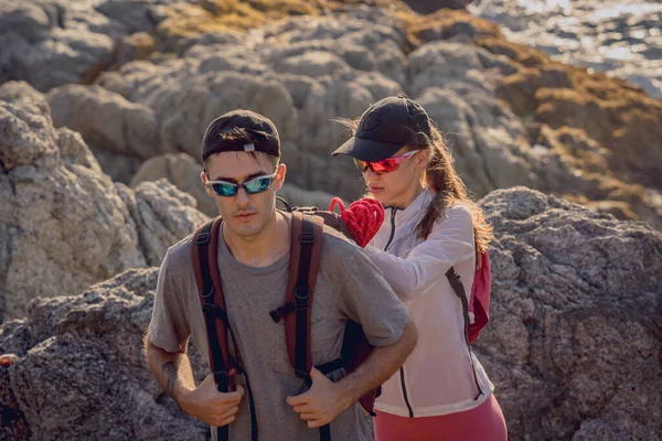 stock image Happy young couple climbs to the top in the mountains near the ocean.