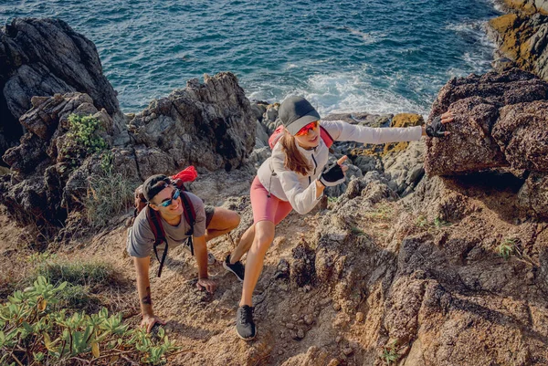 一对快乐的年轻夫妇爬上了靠近大海的山顶 — 图库照片