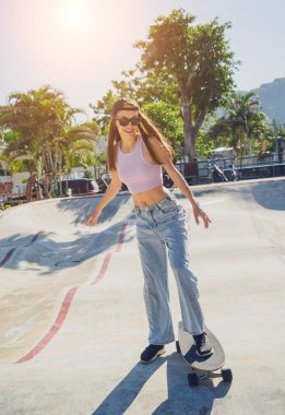 Kaykaylı mutlu genç kadın kaykayın tadını çıkarıyor..