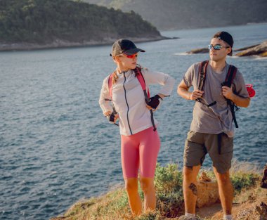 Mutlu genç çift okyanusun yakınındaki dağların zirvesine tırmanıyor..