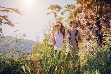 Mutlu genç çift okyanusun yakınındaki dağların zirvesine tırmanıyor..