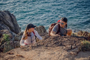 Mutlu genç çift okyanusun yakınındaki dağların zirvesine tırmanıyor..