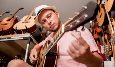 Genç bir müzisyen gitar dükkanında klasik gitar akort ediyor..