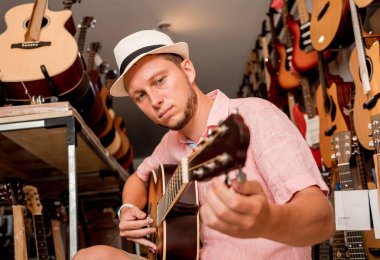 Genç bir müzisyen gitar dükkanında klasik gitar akort ediyor..