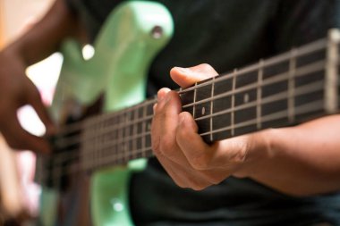 Gitar dükkanında bas gitar test eden genç bir müzisyen..