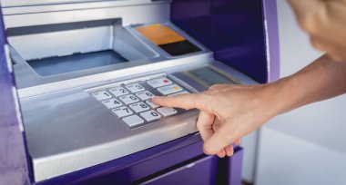Genç bir kadın ATM 'den para çekmek için kartı kullanıyor..