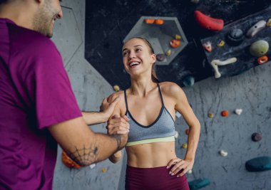 Renkli tutacakları ve ipleri olan yapay bir duvara karşı güçlü bir çift tırmanıcı.