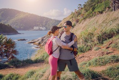 Mutlu genç çift okyanusun yakınındaki dağların zirvesine tırmanıyor..