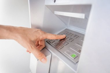 Genç bir kadın ATM 'den para çekmek için kartı kullanıyor..