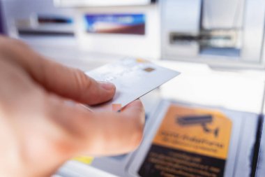 Genç bir kadın ATM 'den para çekmek için kartı kullanıyor..