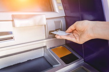 Genç bir kadın ATM 'den para çekmek için kartı kullanıyor..