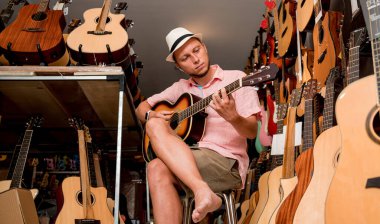 Genç bir müzisyen gitarı gitar dükkanında test ediyor..