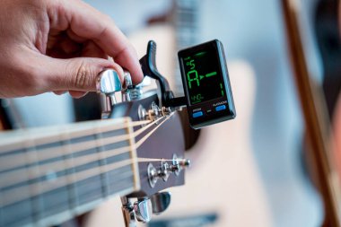 Genç bir müzisyen gitar dükkanında klasik gitar akort ediyor..