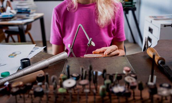 Young female jeweler making jewelry in workshop.