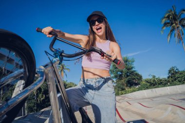 Mutlu genç kadın kaykay parkında BMX 'in tadını çıkarıyor..