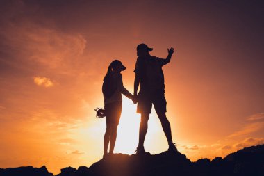 Mutlu genç çift okyanusun yakınındaki dağların zirvesine tırmanıyor..