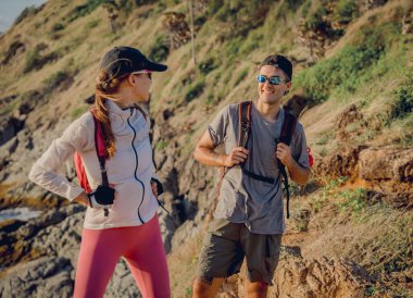 Mutlu genç çift okyanusun yakınındaki dağların zirvesine tırmanıyor..