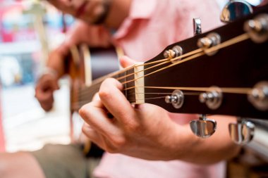 Genç bir müzisyen gitarı gitar dükkanında test ediyor..
