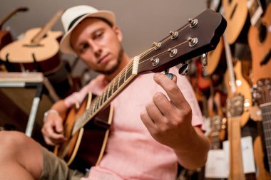 Genç bir müzisyen gitar dükkanında klasik gitar akort ediyor..